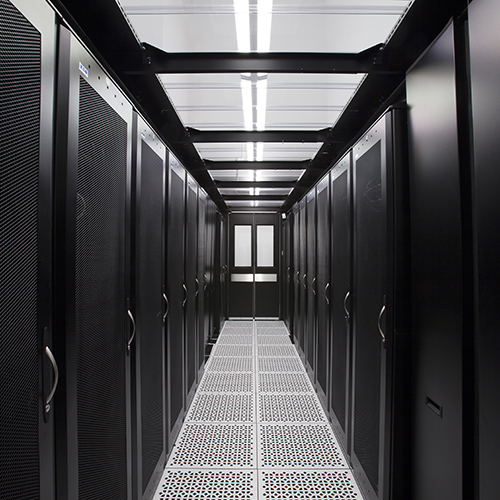 Pasillo de centro de datos con racks de servidores y luz tenue.